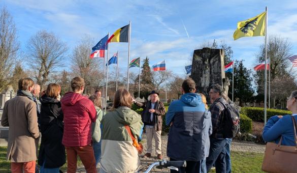 Foto van de gids met een groep aan een monument op de stadsbegraafplaats.