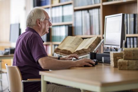 Een vrijwilliger transcribeert aktes uit de schepenbank in het stadsarchief Een vrijwilliger transcribeert aktes uit de schepenbank in het stadsarchief